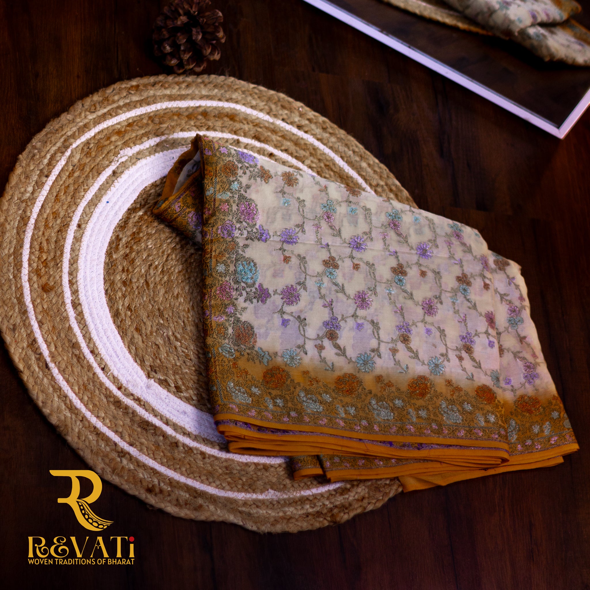 Mustard yellow cotton-silk saree adorned with delicate lavender floral weaves, a cream printed pallu, and soft zari highlights for an elegant finish.