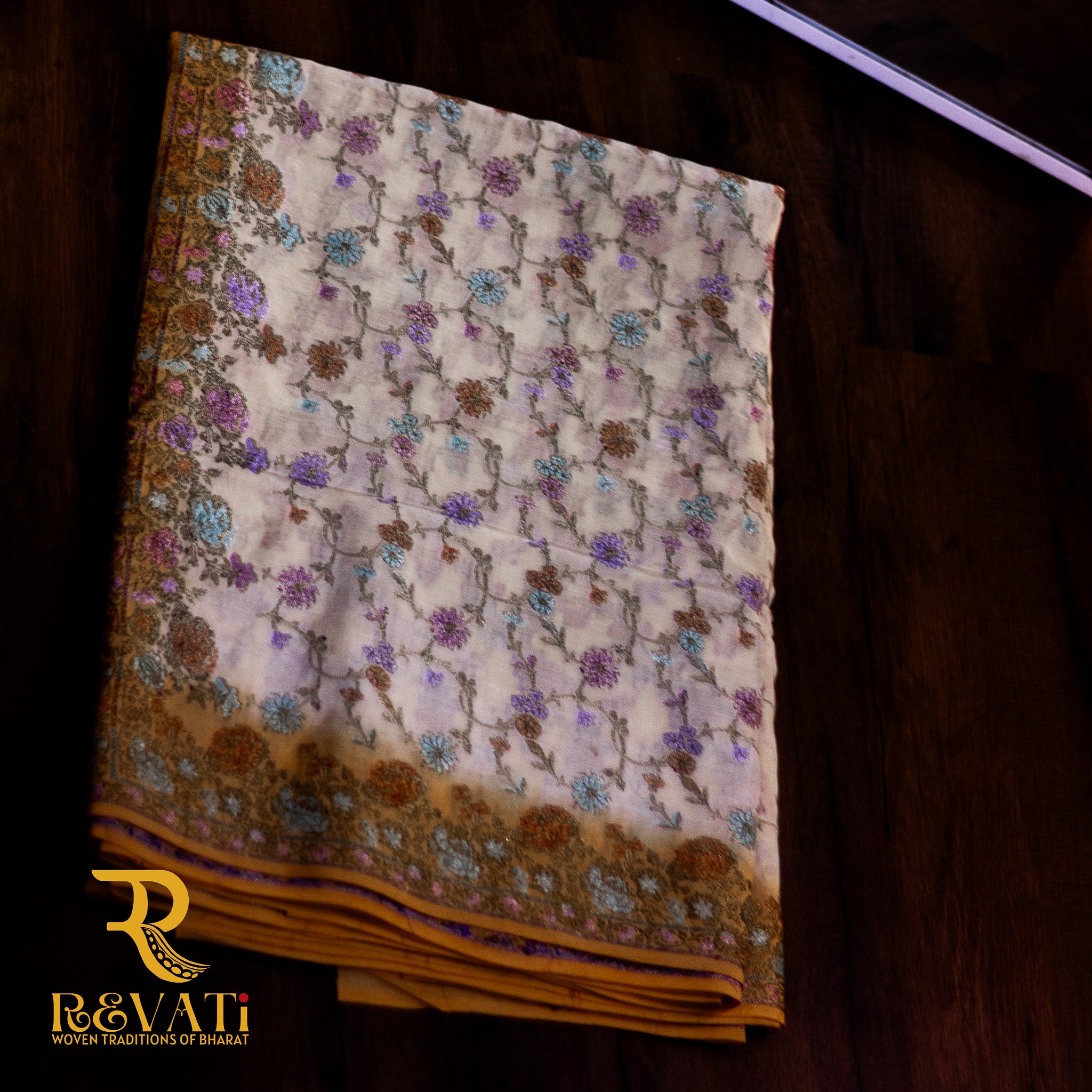 Mustard yellow cotton-silk saree adorned with delicate lavender floral weaves, a cream printed pallu, and soft zari highlights for an elegant finish.