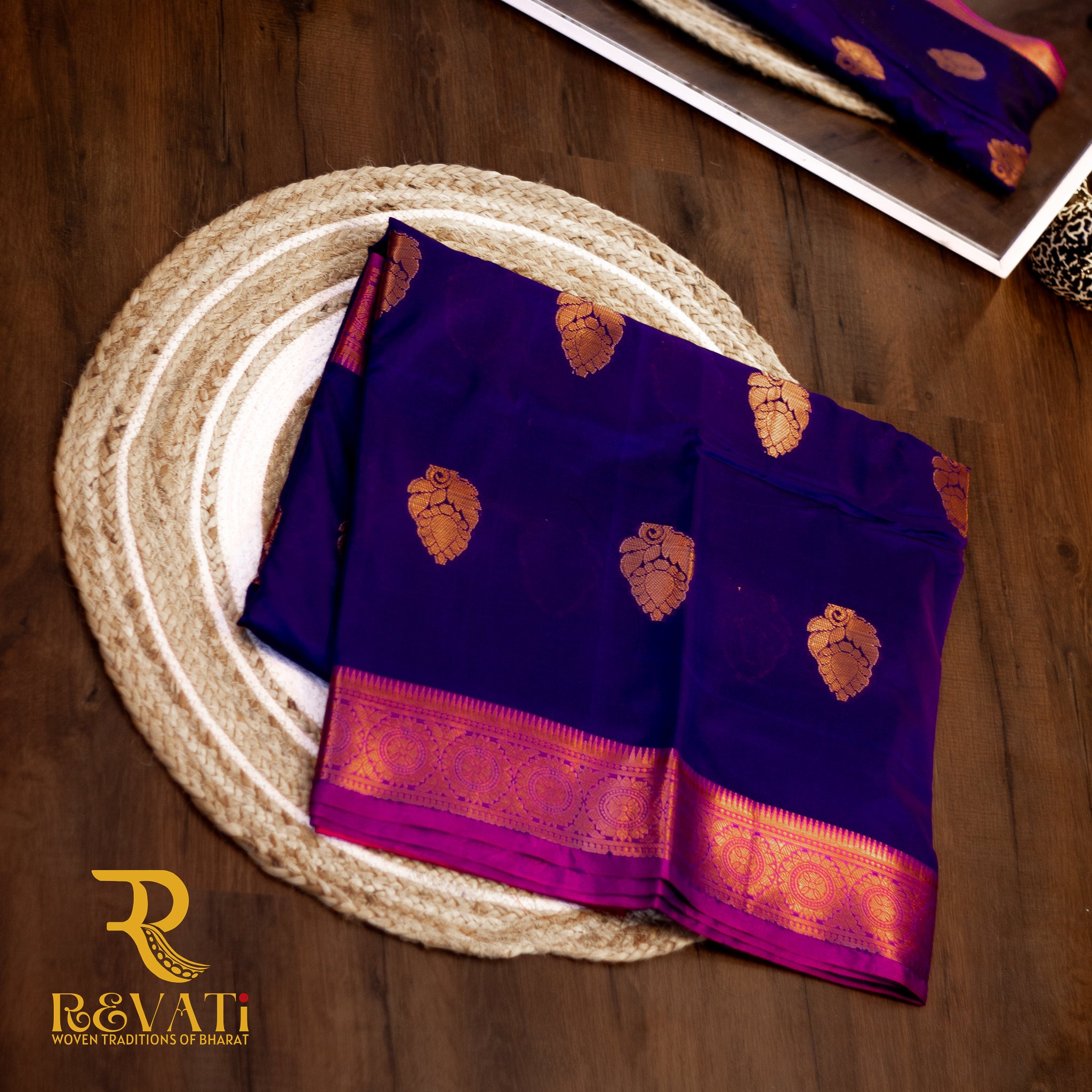 Royal blue and maroon Kanjeevaram silk saree featuring intricate golden leaf and paisley motifs, finished with rich pink-gold woven borders for a timeless, regal look.