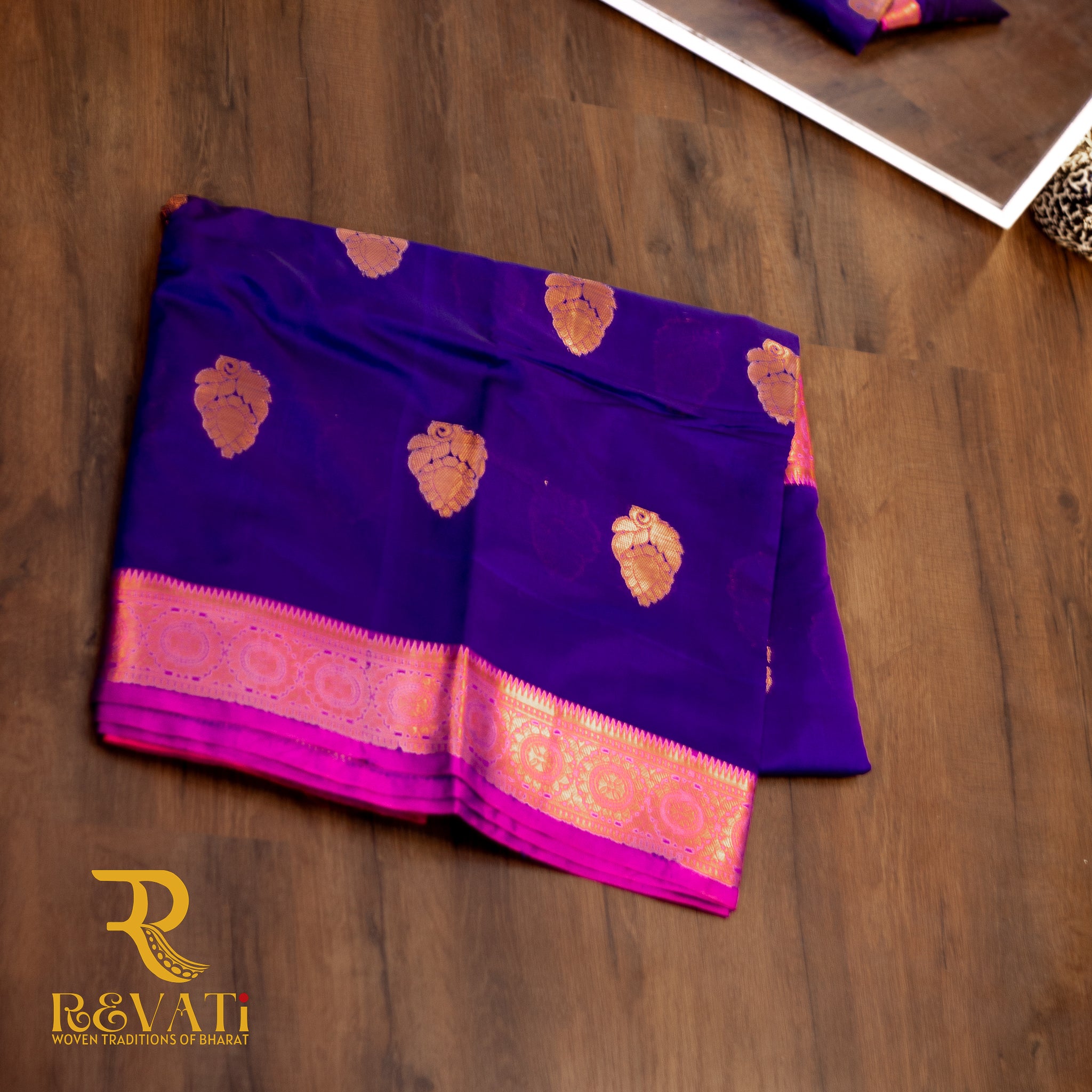 Royal blue and maroon Kanjeevaram silk saree featuring intricate golden leaf and paisley motifs, finished with rich pink-gold woven borders for a timeless, regal look.