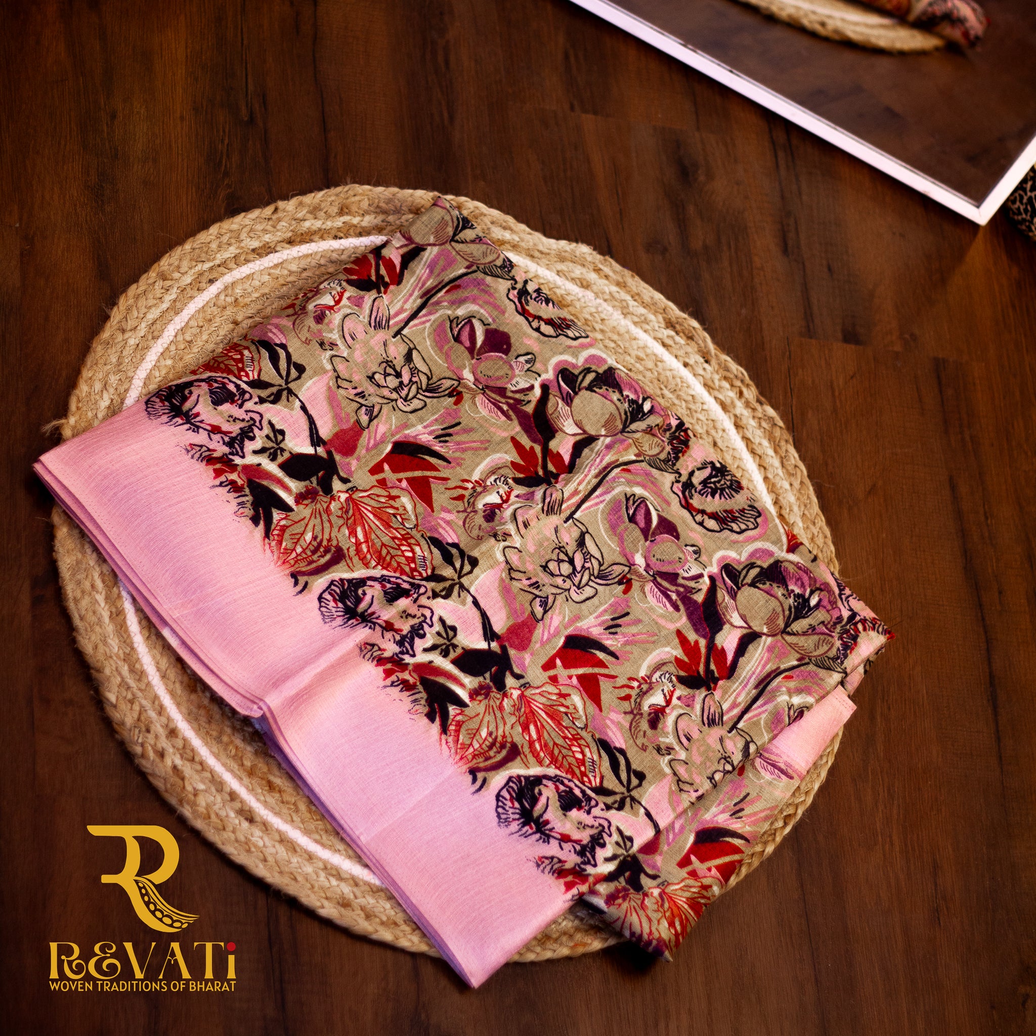 Beige linen-blend saree adorned with bold pastel florals in soft hues and finished with an elegant pink woven border.
