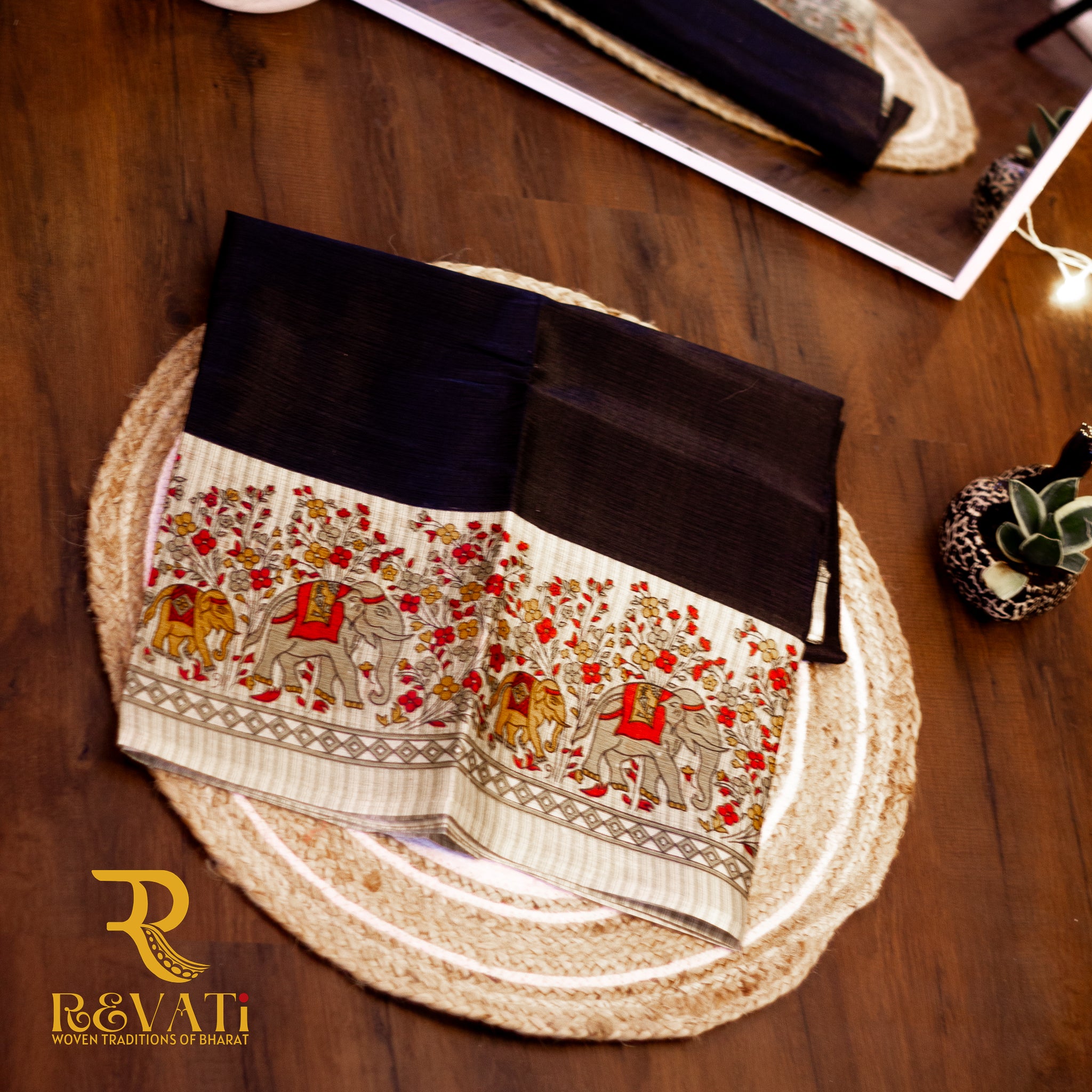 Jet black handloom silk saree with a beige Madhubani-inspired pallu featuring floral and elephant motifs.